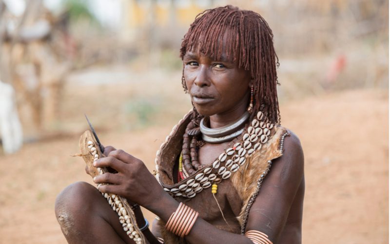 Vrouw met micro-locs afgebeeld in Ethiopië zittend op de grond