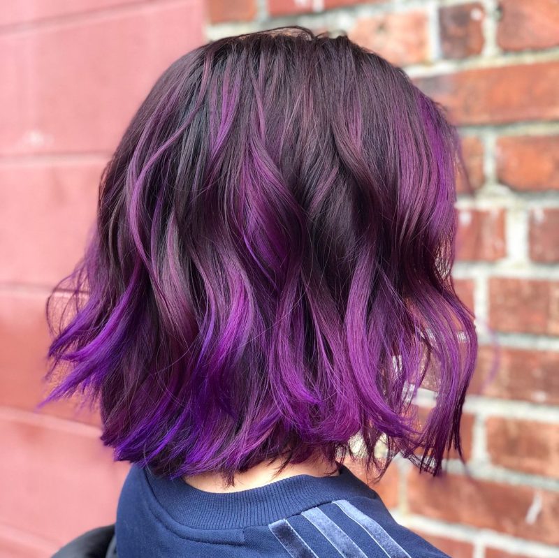 Zwart en paars haar met paarse balayage golven geschilderd in de onderste helft van het haar