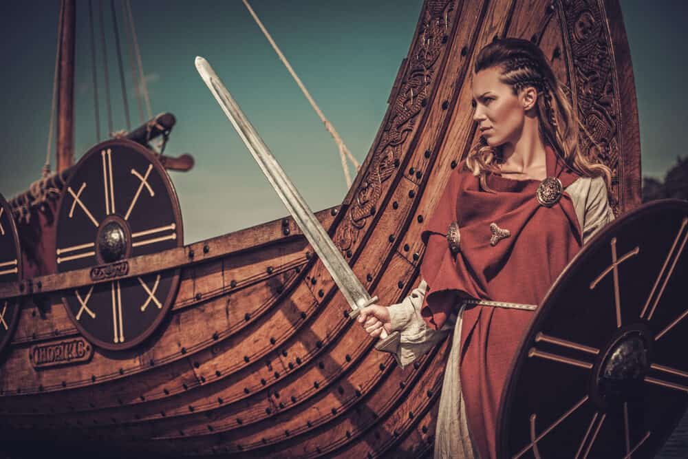 Zelfverzekerde Vikingvrouw met gevlochten haar die een reeks vijanden met haar zwaard en schild van zich afhoudt.