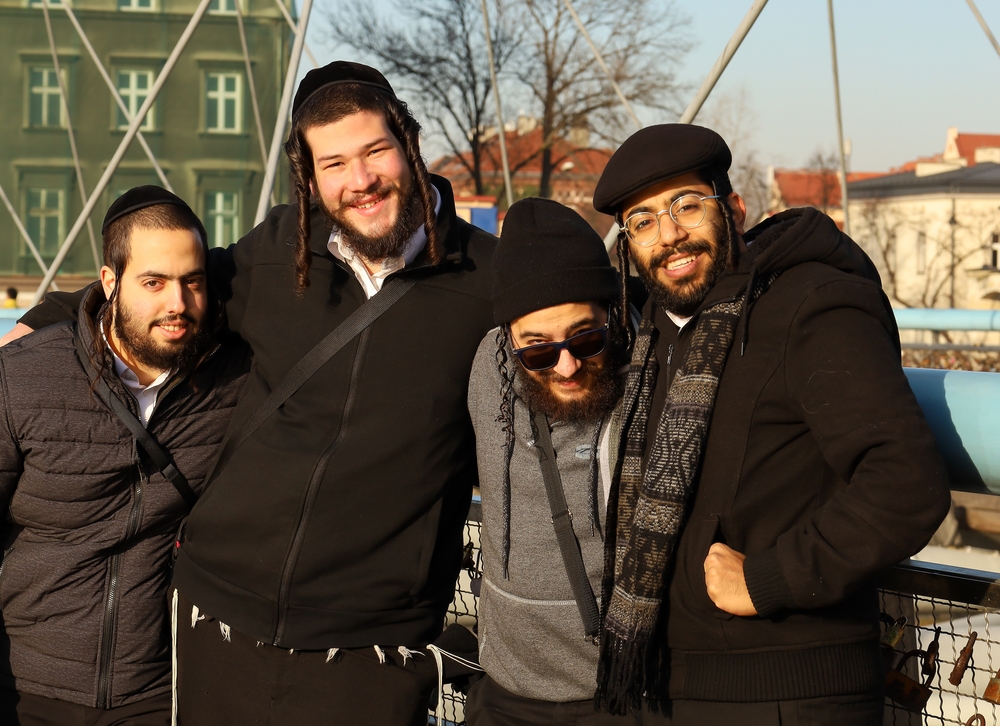 Vier man in Polen lachen en omhelzen elkaar voor een stuk over waarom hebben joodse mensen krullend haar