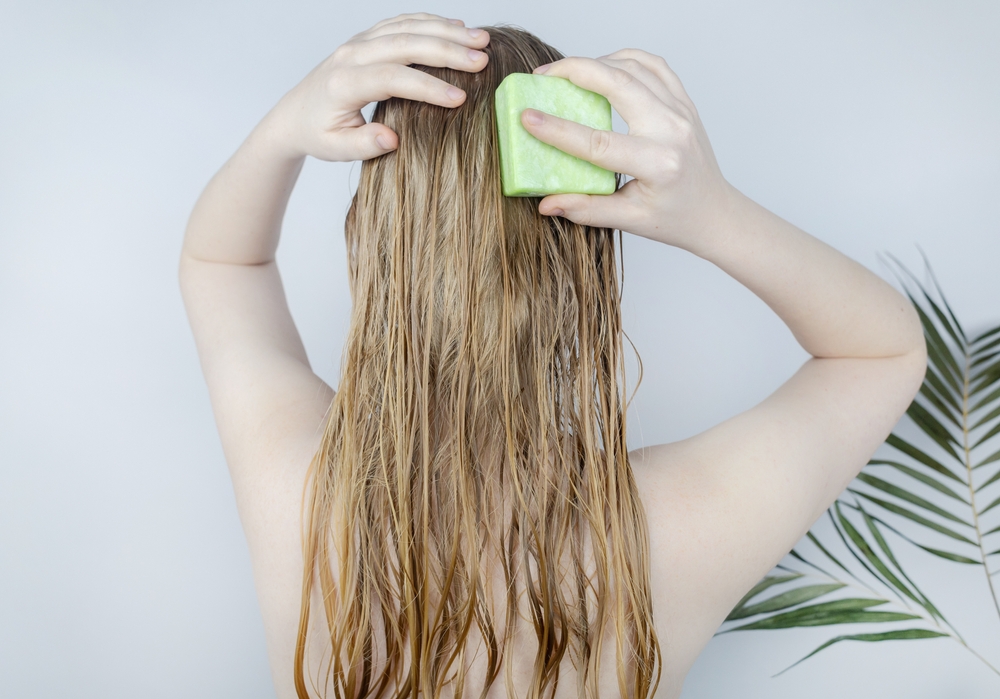 Vrouw verzorgt haar gebleekte haar dat uitvalt met behulp van een shampoo bar