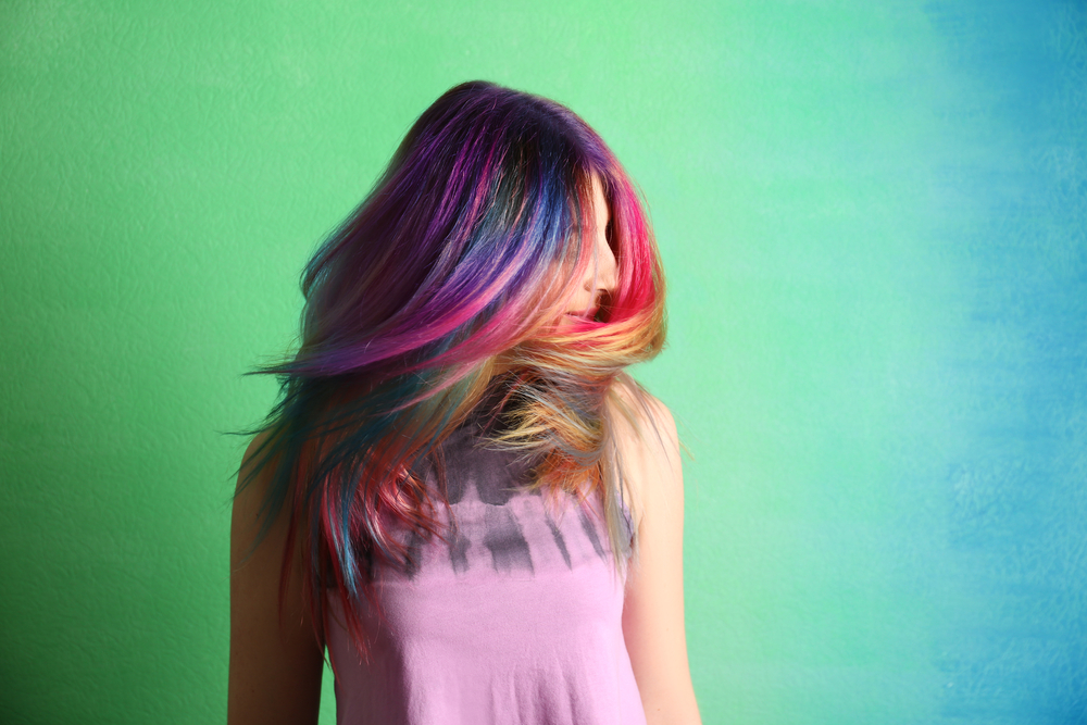 Prismatic Oil Slick Haar op een vrouw in een groene en blauwe kamer