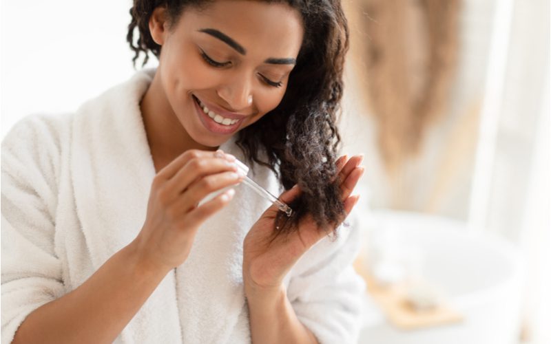 Vrouw die een van de beste straightening producten voor zwart haar op haar natte haar aanbrengt