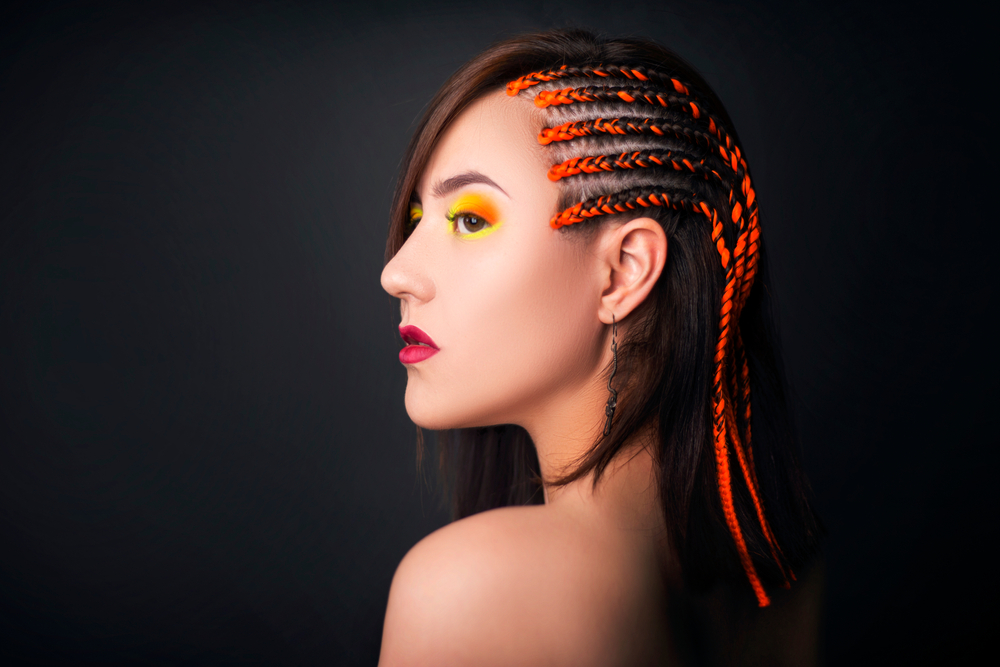 Thaise vlechten met cornrows aan de zijkant op een Aziatische vrouw met gele make-up rond haar ogen en rode lippen