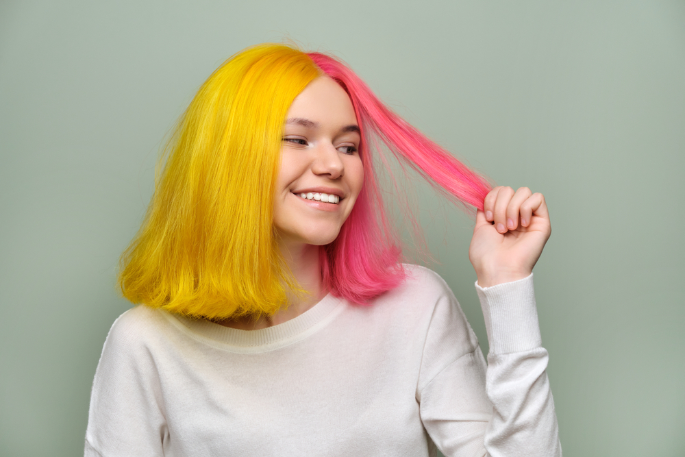 Goldenrod Yellow en Pink Split Dye, een van de beste onnatuurlijke haarkleuren voor blauwe ogen, op een vrouw in een witte trui
