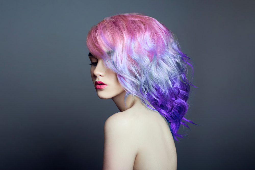 Bubblegum Pink to Violet Ombre, een van de beste onnatuurlijke haarkleuren voor blauwe ogen, op een vrouw in een grijze kamer