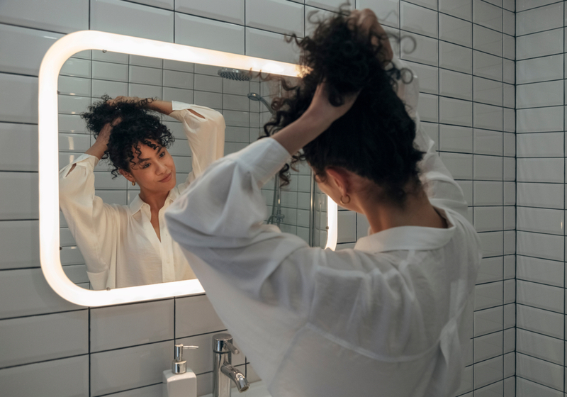 Vrouw die haar krullen omhoog trekt als een manier om 3C krullend haar te stylen