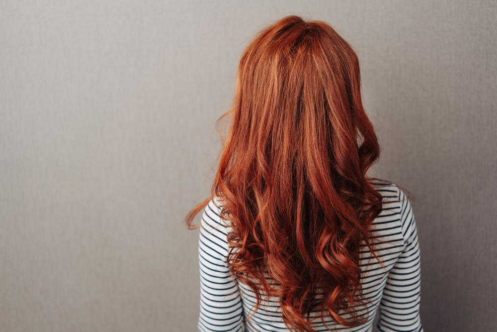 Medium Auburn, een van de beste winter haarkleuren, op een vrouw met een zwart-wit gestreept shirt