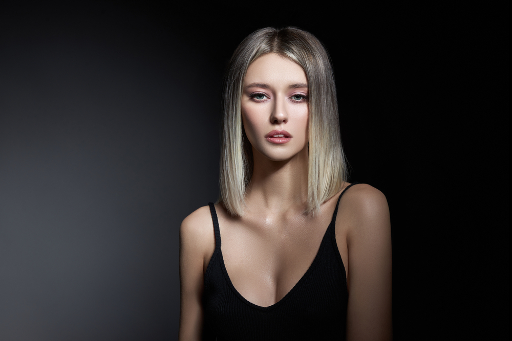 Een van de beste haarkleuren voor een bleke huid, Ash Brown to Blonde Balayage, op een vrouw in een zwart hemd