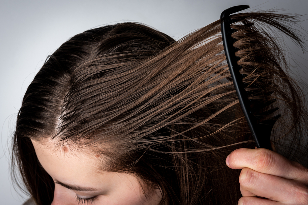 Afbeelding van een meisje dat zich afvraagt waarom haar haar wasachtig is door er een kam doorheen te halen