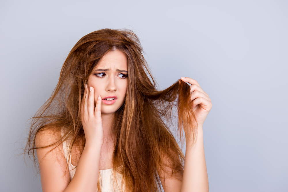 Is Aussie Shampoo Goed Voor Haarproblemen sectie met een vrouw die naar haar beschadigde haar kijkt