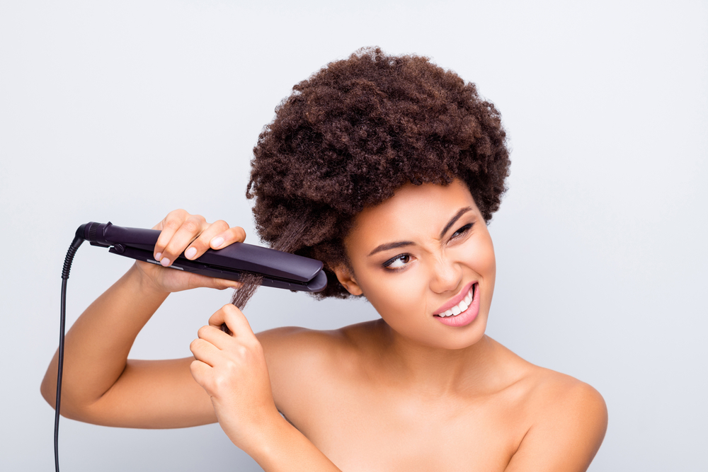 Het beeld van een zwarte vrouw die haar haar met hitte voor een stuk op relaxeralternatieven voor zwart haar rechtmaakt