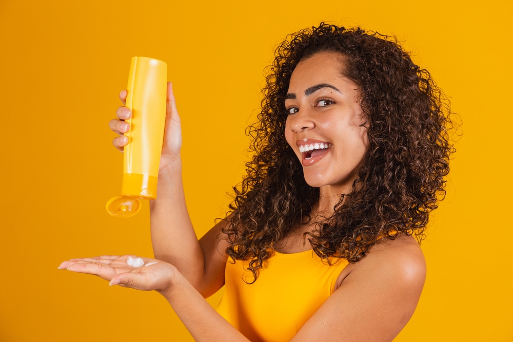 Vrouw met haarcrème afgebeeld die het in haar hand spuit voor een stuk over de beste relaxer alternatieven voor zwart haar