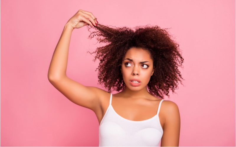 Vrouw die haar haar vasthoudt en omhoog en naar rechts kijkt voor een stuk over hoe krullend haar te drogen