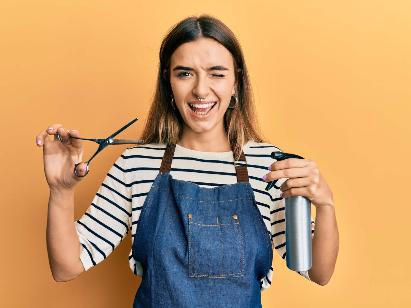 Liberale hairstylist met een septum ring die kapgereedschap omhoog houdt