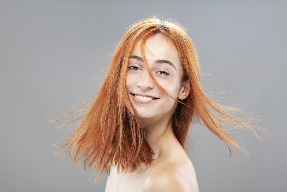 Vrouw met oranje haar lacht voor een stuk over de beste haarkleuren voor blauwe ogen