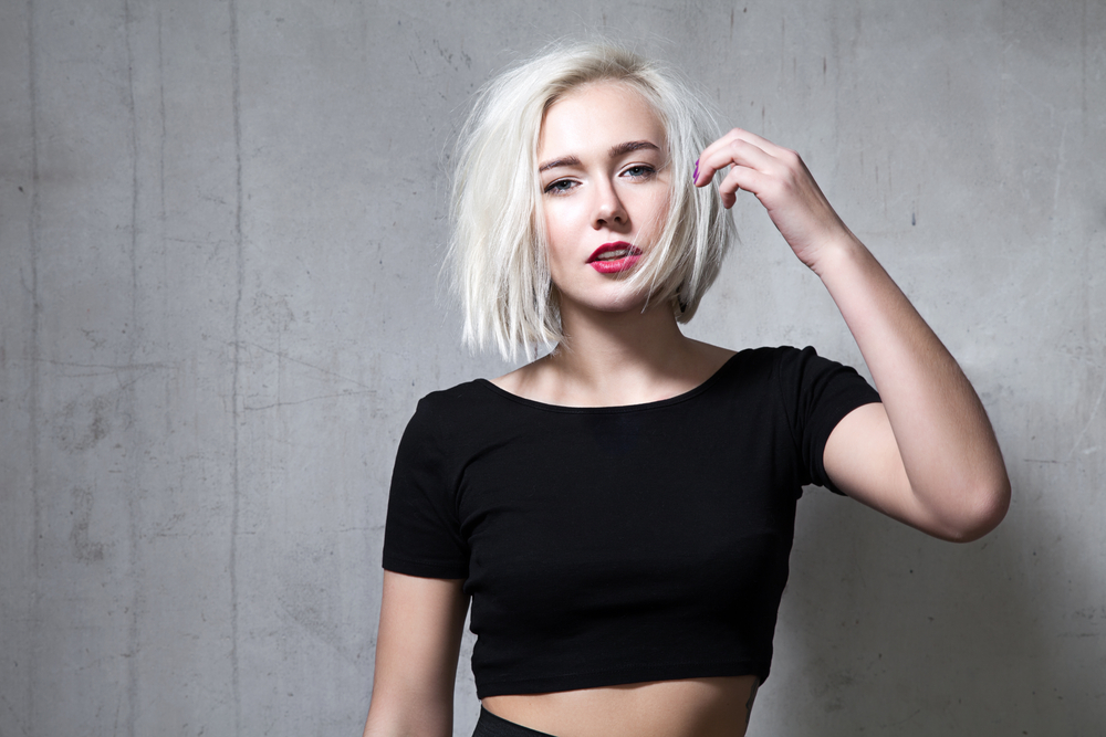 Vrouw met wit haar in een zwarte crop top afgebeeld voor een stuk over de beste haarkleuren voor blauwe ogen