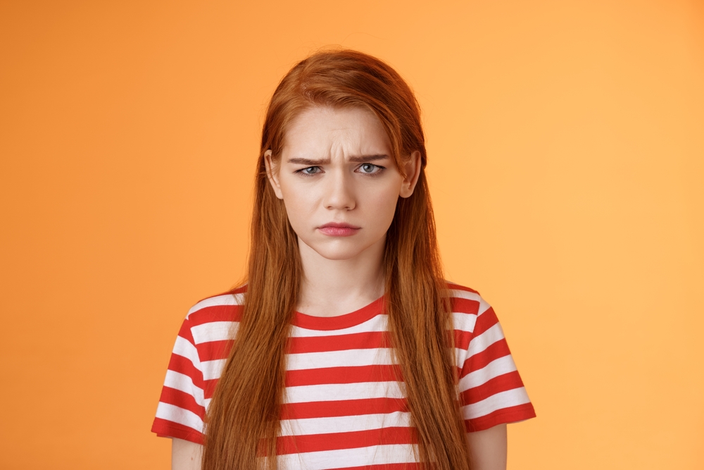 Roodharige in een oranje kamer kijkt beledigd omdat iemand haar een gember noemde