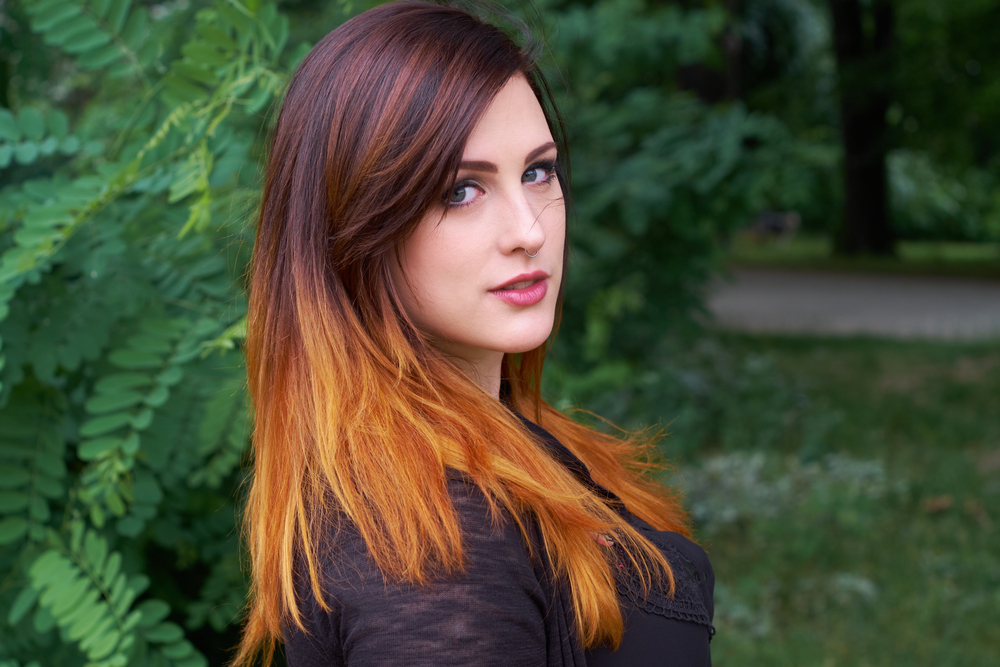 Vrouw met auburn highlights buiten afgebeeld ter illustratie van de beste haarkleuren voor neutrale huidtinten