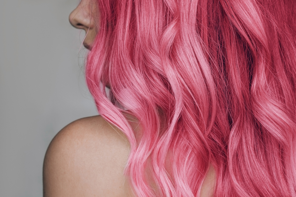 Voor een gids van de minst natuurlijke haarkleuren voor koele huidskleuren, ziet een vrouw met roze haar er links