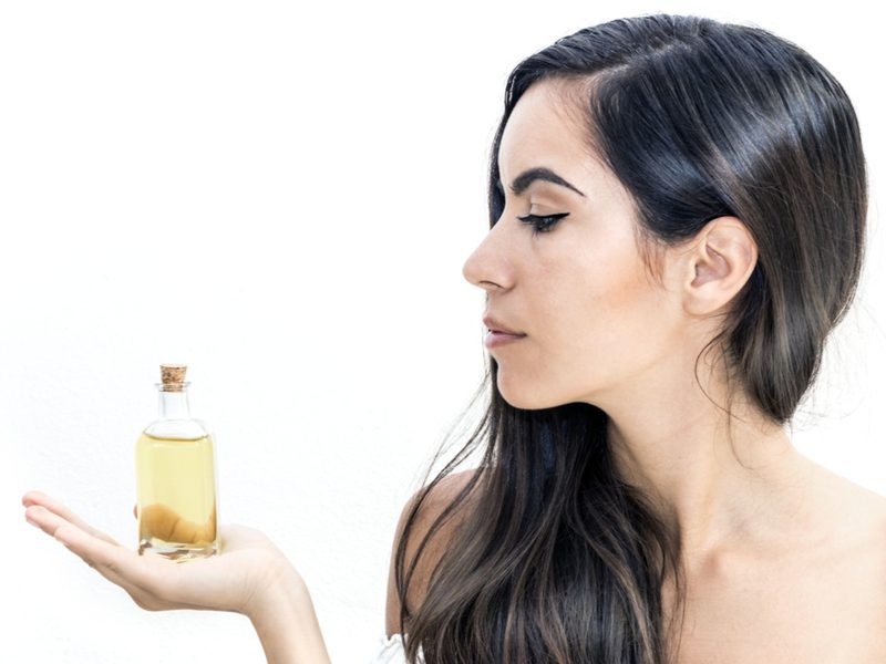 Vrouw met een flacon Arganolie voor het haar in haar hand