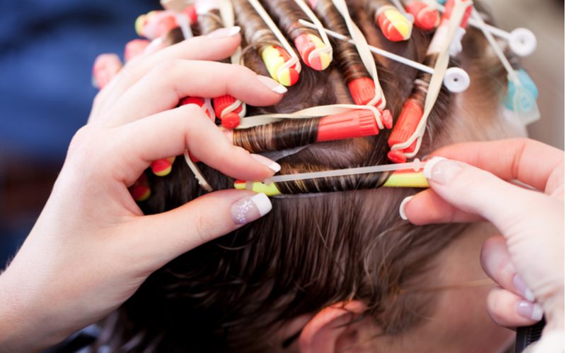 Vrouw met kort haar krijgt een permanent van schuimrollen op heel kort haar