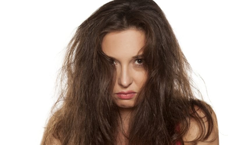 Voor een stuk over het beste haarserum pruilt een vrouw met kroeshaar terwijl ze naar de camera kijkt.