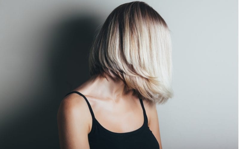 Lady with Medium Hair staat met haar haar dat het gezicht bedekt en haar zwarte tank die wat decolleté toont.