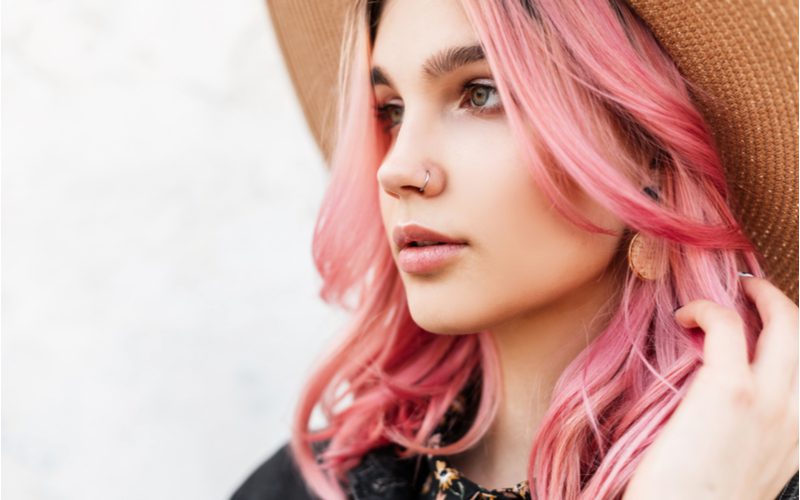 Vrouw met roze haar draagt een boho hoed voor een stuk over hoe je gordijn pony te knippen