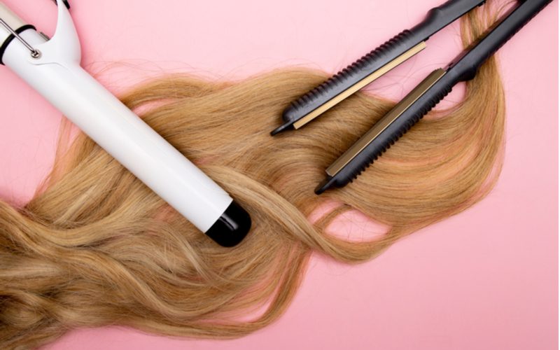 Om te illustreren hoe je natuurlijk dikker haar krijgt, een paar hete hulpmiddelen die je beter niet kunt gebruiken bovenop blond haar op een roze achtergrond