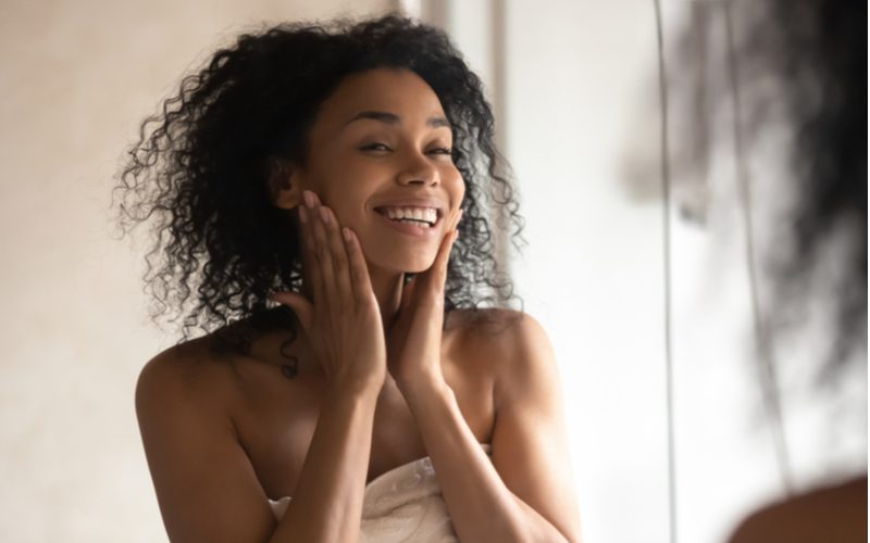 Zwarte vrouw in een handdoek komt net uit de douche ter voorbereiding op het krijgen van box braids