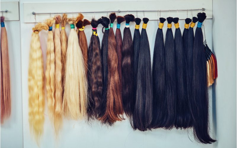 Tros haarextensies in verschillende kleuren hangend aan een deur om een stap te illustreren hoe je box braids op jezelf kunt doen.