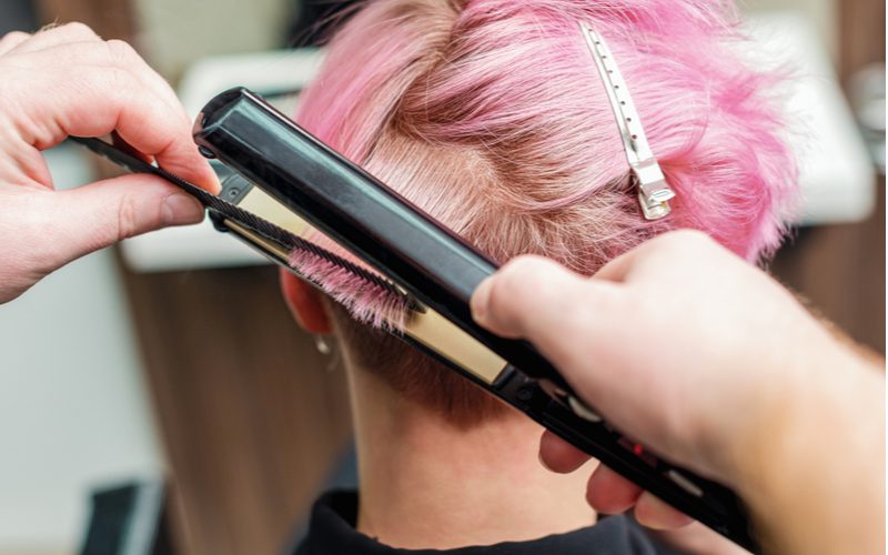 Rozeharige liberale vrouw met gek roze haar krult haar echt korte haar met een stijltang