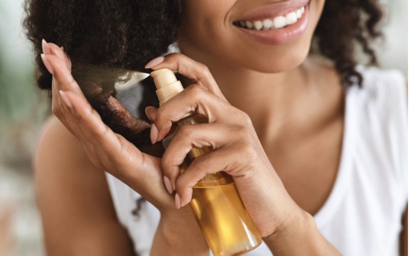 Vrouw hydrateert haar haar met serum om van kroeshaar af te komen