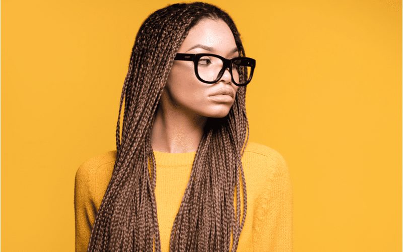 Vrouw met lange limonadedoos microvlechten draagt een bril voor een stuk over soorten vlechten