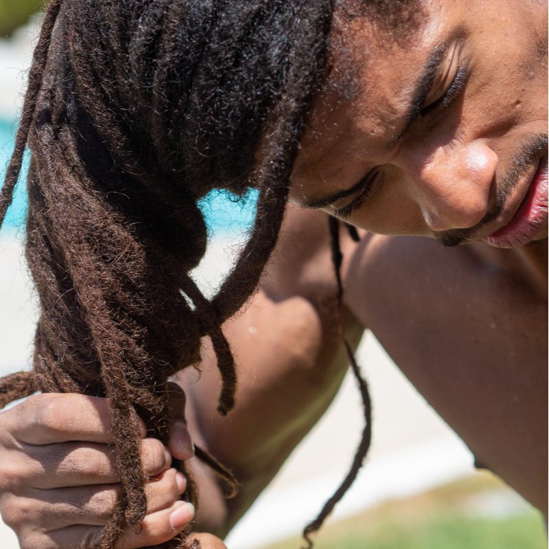 Man buigt voorover terwijl hij zijn lokken draait om de dreadlocks die aan de wortel dunner worden te fixeren