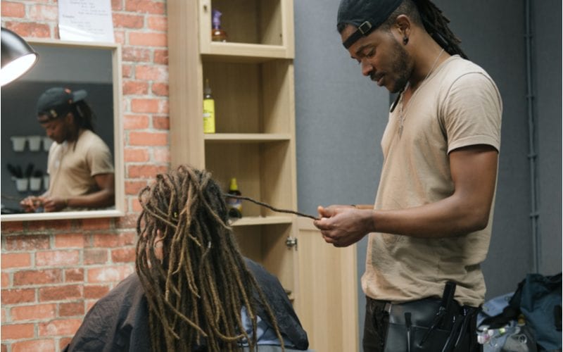 Close up van een man die dreads begint voor een man in een Afrikaans vlechtatelier