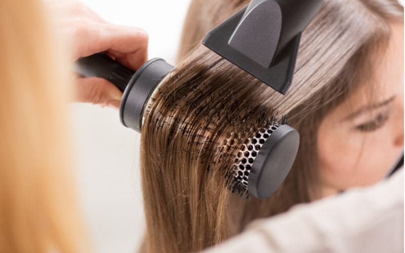 Voor een stuk over wat is een hair blowout, een vrouw die er een krijgt in een salon met behulp van een ronde borstel en een hair smoother