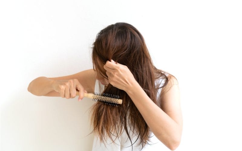 Aziatische vrouw die haar haar borstelt ter voorbereiding van een blowout