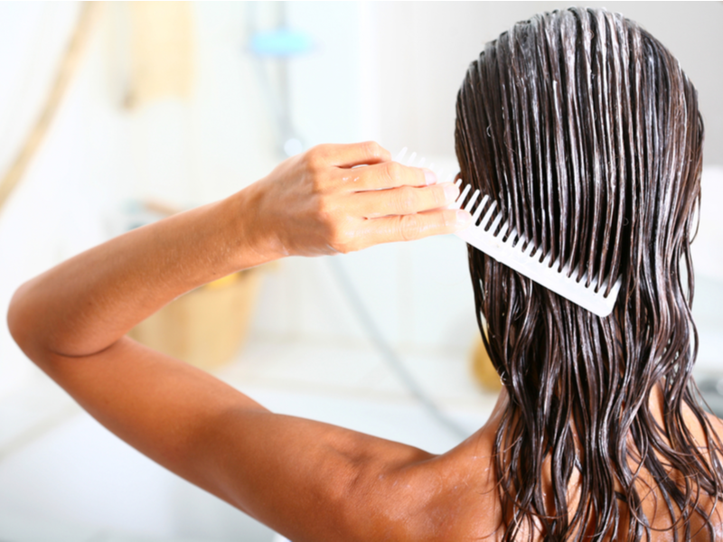 Vrouw onder de douche die een diepe conditioner gebruikt om te voorkomen dat haar haarkleur vervaagt.