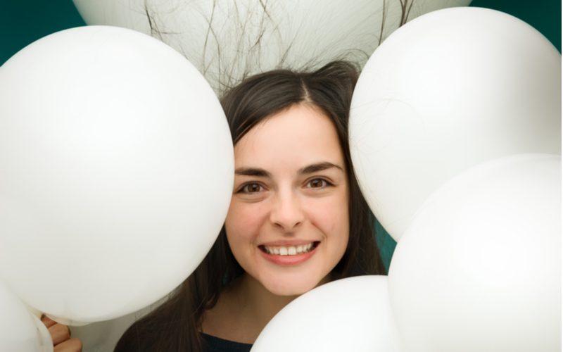 Vrouw lachend in het midden van een stel ballonnen voor een stuk over hoe je van statisch haar af komt