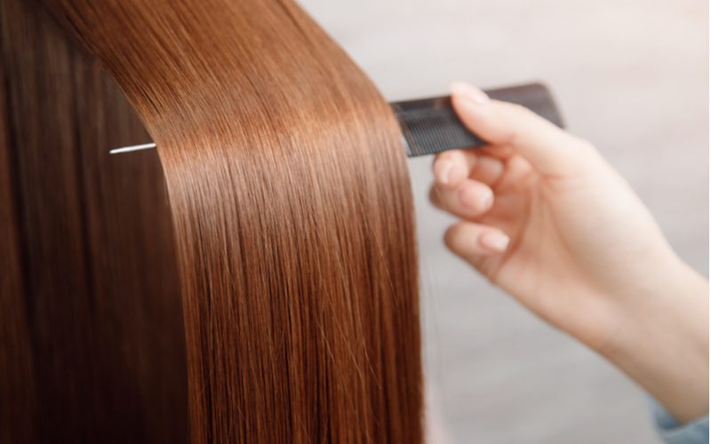 Close-up van een vrouw die met een kam haar haar omhoog trekt naar de camera om te antwoorden waar haar van gemaakt is.