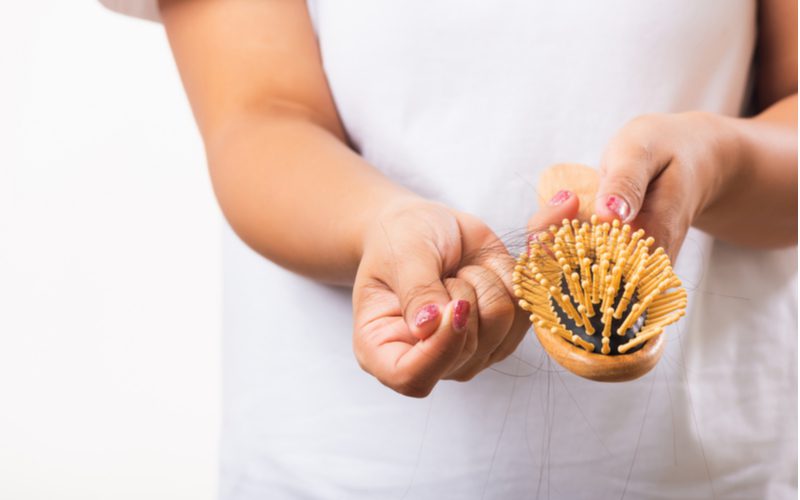 Voor een stuk over hoe een haarborstel schoon te maken, een vrouw die haren uit de tanden van haar houten borstel trekt