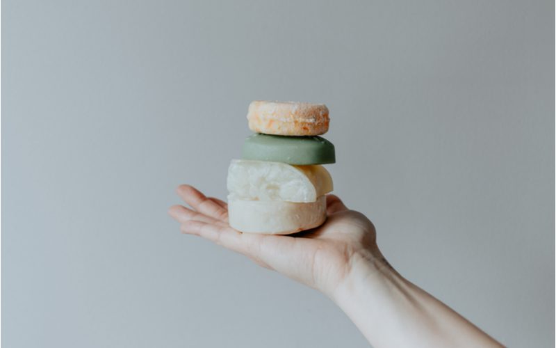 Verschillende soorten shampoo bars worden vastgehouden door een hand voor een stuk over de beste shampoo bars