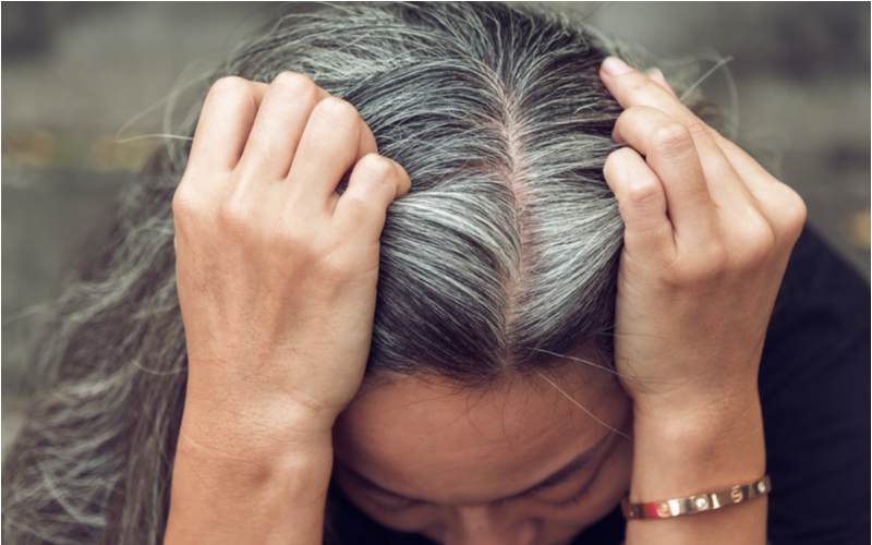 Vrouw laat zien wat er gebeurt met grijs haar na gebruik van paarse shampoo