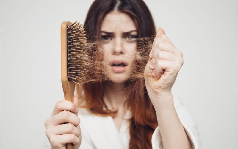 Jonge vrouw die een borstel en haar vasthoudt voor een blogpost over wat fijn haar is