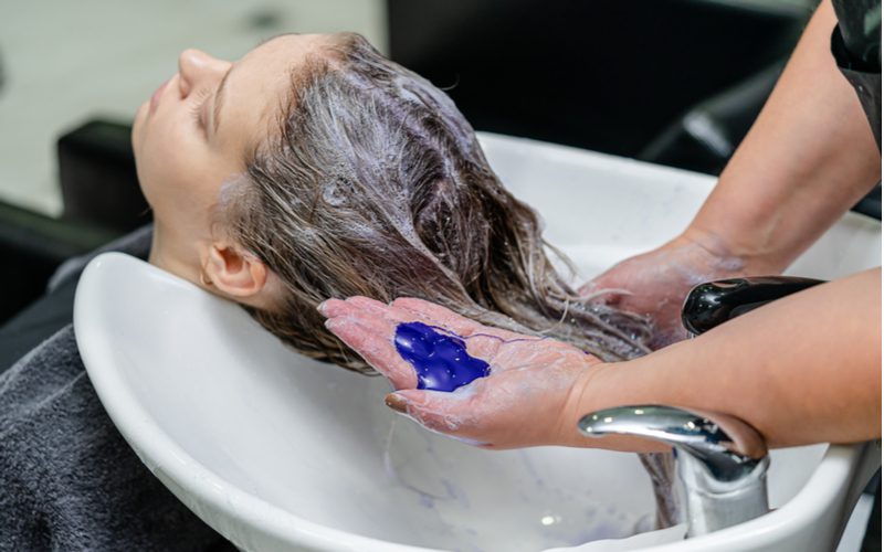Vrouw die haar haar kleurt met paarse shampoo