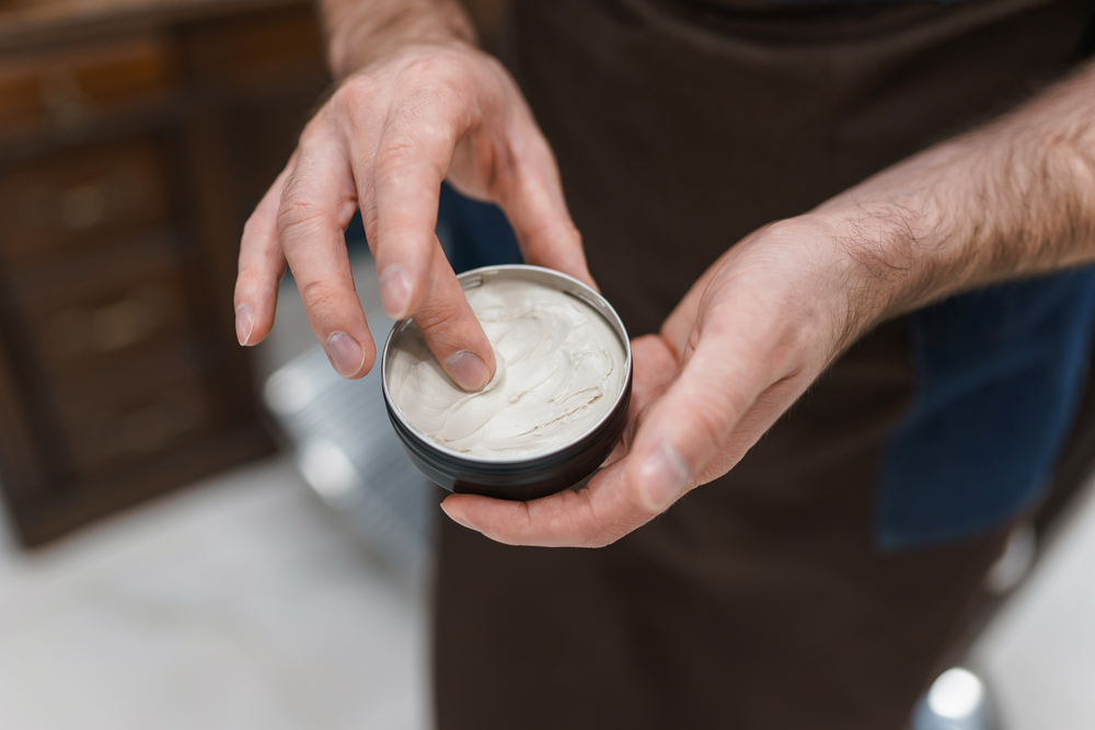 Man gebruikt pommade op zijn vinger voor een stuk over de beste haarlak alternatieven