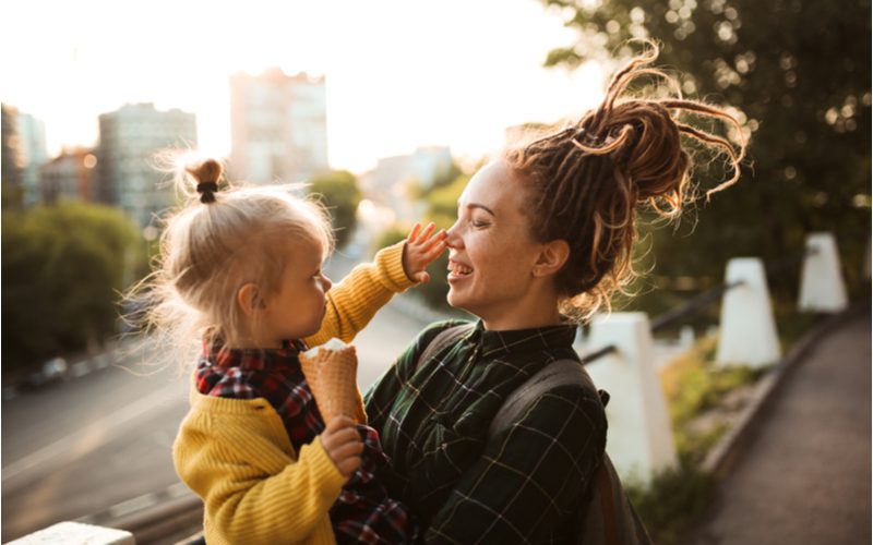 Voor een stuk over dreadlocks, een vrouw met deze stijl houdt een baby vast terwijl haar haar boven haar hoofd is vastgebonden.