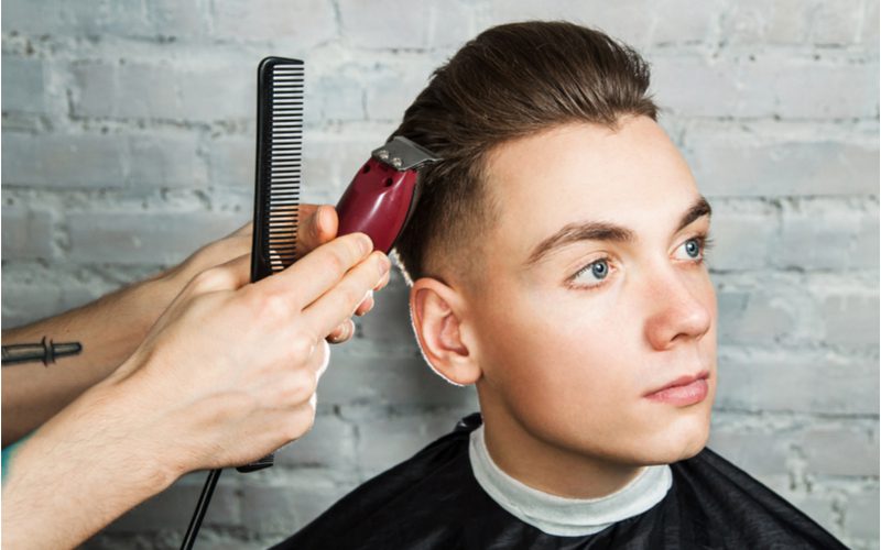 Guy With Slicked-Back Hair With Undercut Wordt geschoren met een set rode elektrische tondeuse